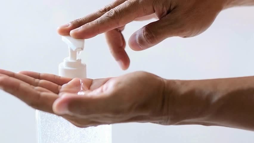 Person dispensing liquid soap onto hands for hygiene