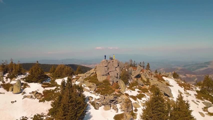 Mountaintop View: Hikers on Rocky Summit with Patches of Snow