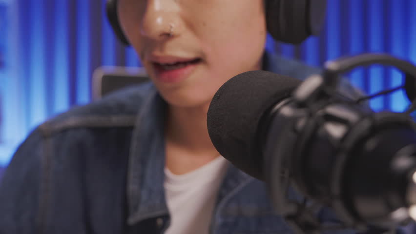 Macro shot of professional microphone in use by content creator during a podcast or livestream recording