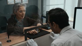 Over the shoulder shot of Indian gemologist carefully examining tiny gemstones with tweezers, brought by elderly woman in jewelry store - Powered by Shutterstock - Get 15% off with code: PIKWIZARD15