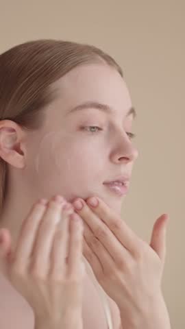 VERTICAL VIDEO Woman and face wash, daily skincare routine. Young girl gently applying foaming cleanser. Morning beauty routine, clean and aesthetic. The concept of a facial cleansing foam advertising