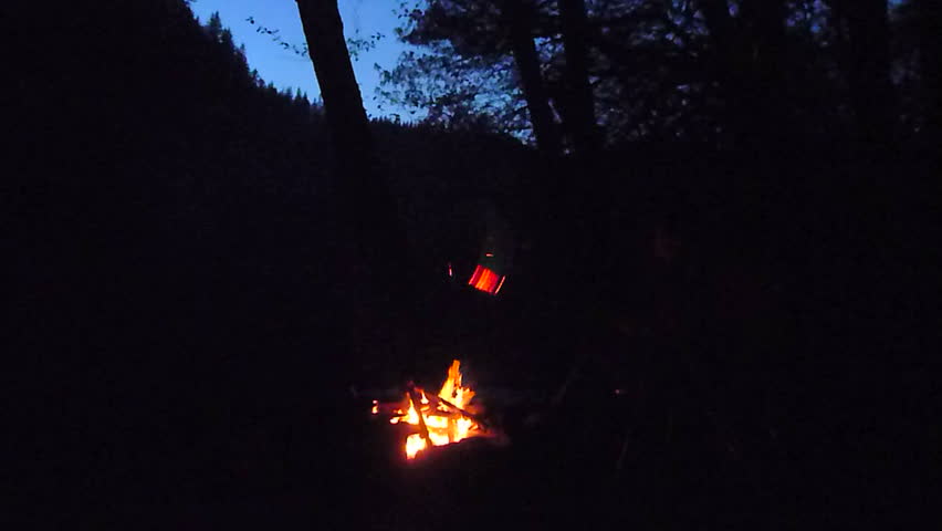Man builds a camp fire for his woman at camp site at night, time lapse.