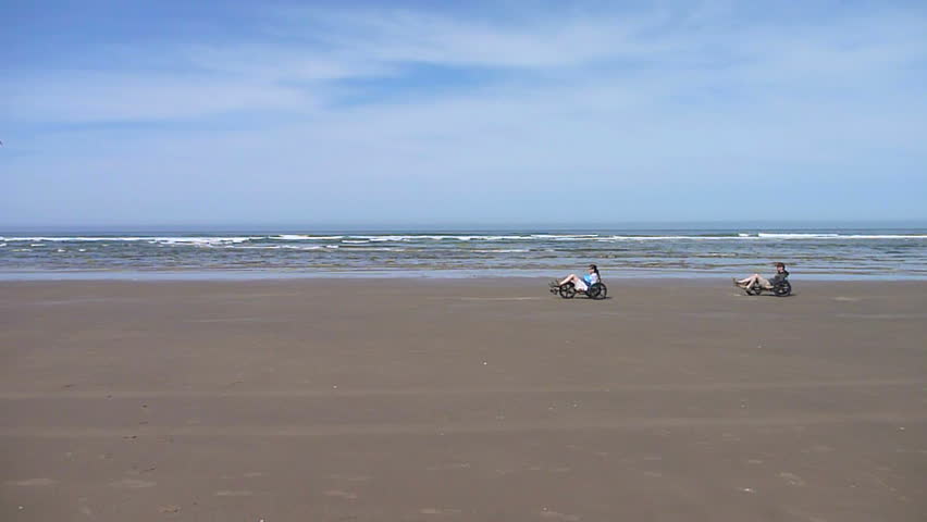 Man and woman riding bikes at Cannon Beach, Oregon on sunny day.