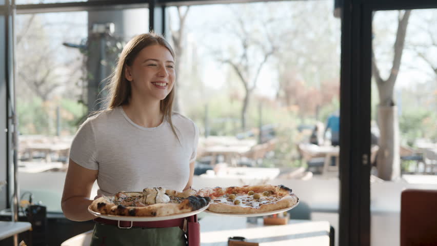 Friendly waitress serving delicious pizza to a young couple enjoying a romantic lunch date in a modern restaurant