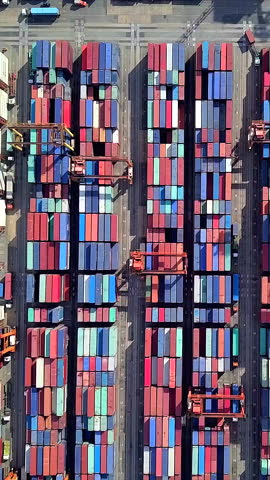 Vertical video of a port and a large number of containers waiting to be loaded onto a cargo ship.
