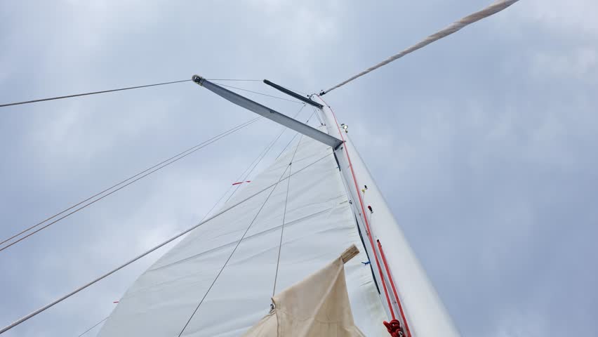 Upward view of sailboat mast and ropes stretching into cloudy Tenerife sky, 4K