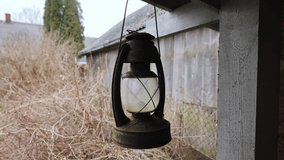 Worn kerosene lantern hangs still near weathered barn in overgrown rural yard - Powered by Shutterstock - Get 15% off with code: PIKWIZARD15