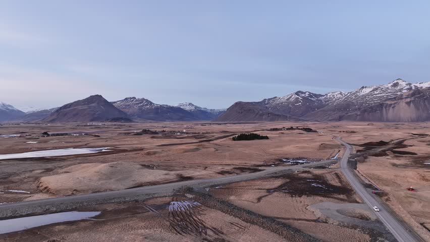 Aerial view of Hafnarnes and the vast Hornafjörður lagoon landscape with Vatnajökull glacier in the distance, surrounded by snow-capped mountains in southeast Iceland.