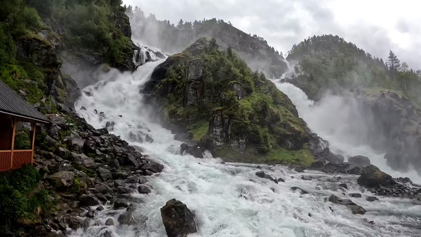 The majestic Latefossen waterfall in Norway, cascading down lush green cliffs under an overcast sky