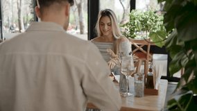 Young couple sharing wood fired pizza and crisp white wine, enjoying intimate lunch date at stylishly modern restaurant with natural light streaming through window - Powered by Shutterstock - Get 15% off with code: PIKWIZARD15
