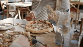 Women sharing slice of gourmet pizza, sipping white wine while enjoying casual dining experience at rustic restaurant table - Powered by Shutterstock - Get 15% off with code: PIKWIZARD15