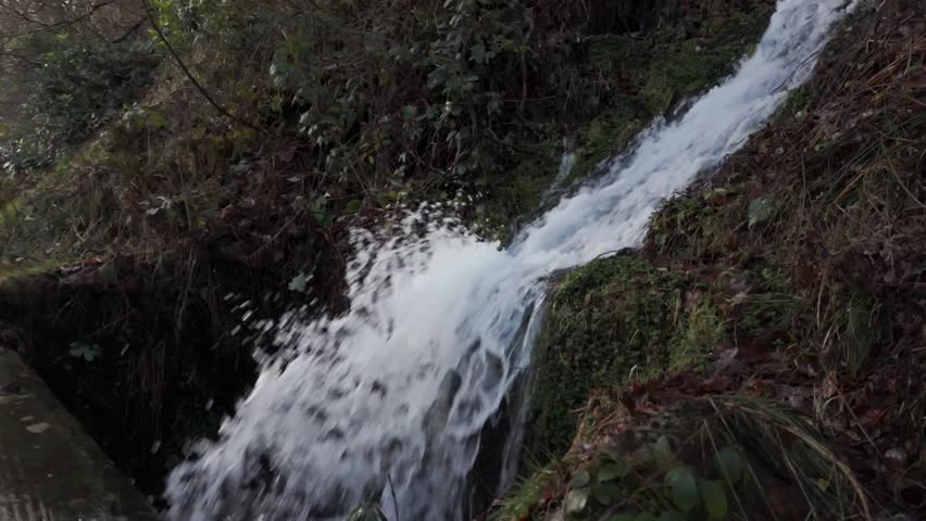 A powerful water flowing off the hillside into Derwent reservoir surrounded by vegetations in Hope valley, Derbyshire, UK