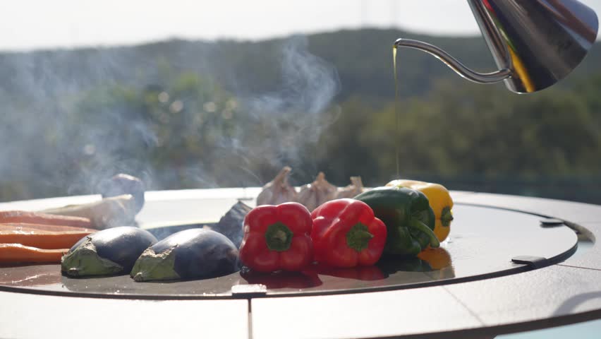 oil being drizzled over vegetables and meats whilst cooking on an open bbq
