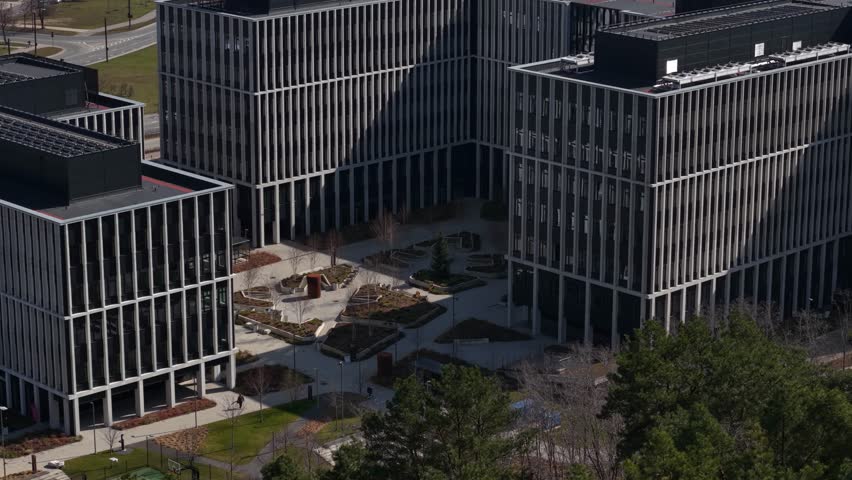 Aerial view of contemporary office buildings arranged around a landscaped courtyard with walking paths and minimal greenery.