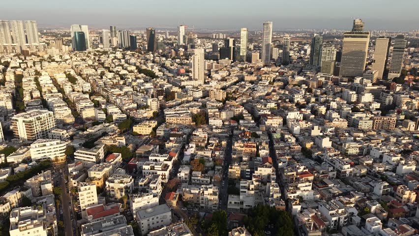 Aerial view capturing the warm glow of sunset over Tel Aviv, Israel, highlighting dense urban architecture.
