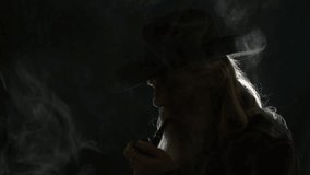 Old bearded cowboy silhouette, backlit in black room, smokes pipe - Powered by Shutterstock - Get 15% off with code: PIKWIZARD15