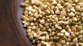 Uncooked green buckwheat grains falling into a wooden bowl in slow motion. Dried dietary ingredient. Macro shot. Rotation - Powered by Shutterstock - Get 15% off with code: PIKWIZARD15