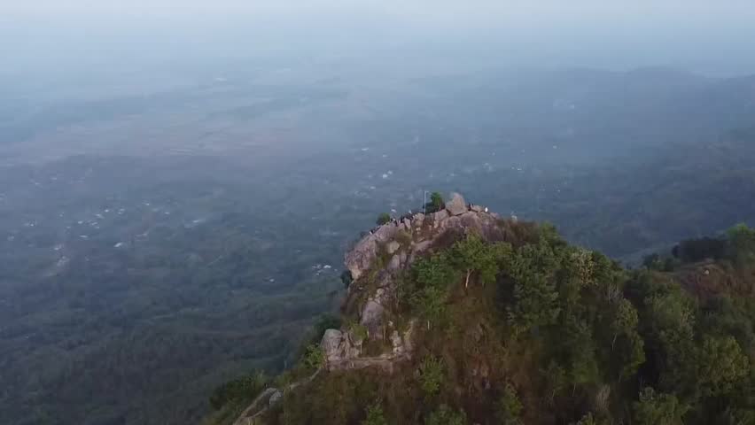A hill filled with large rocks at the top of the hill, with beautiful natural scenery around it in Indonesia