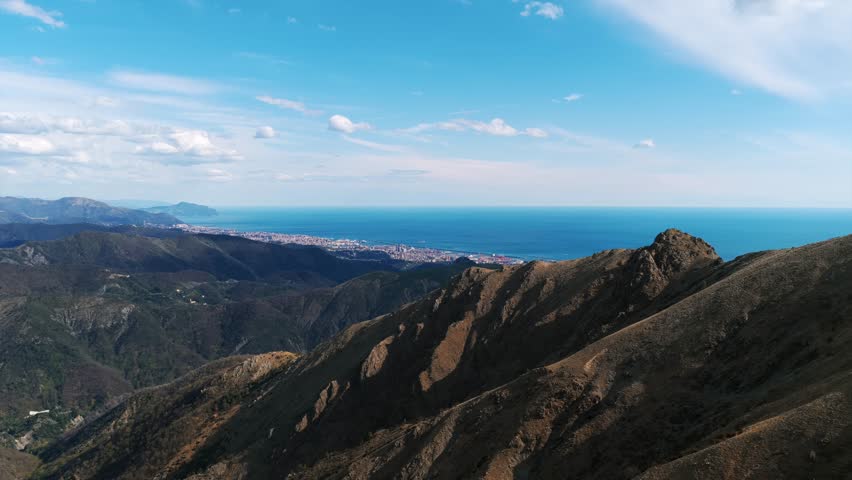 View From Ligurian Apennines With Rugged Peaks In Foreground, Overlooking Coastline And Ligurian Sea In Liguria, Italy. wide aerial shot