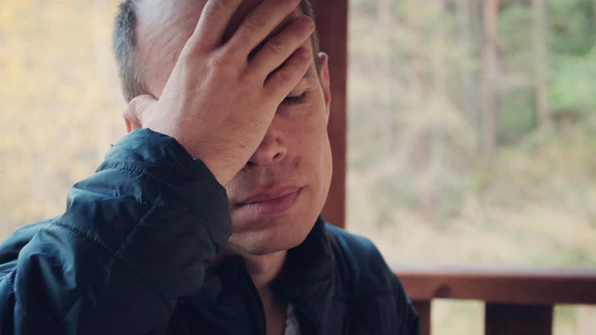 A middle-aged man touches his head with a pained expression, showing signs of a severe headache. Perfect 4K video for health, stress, and medical-related content.