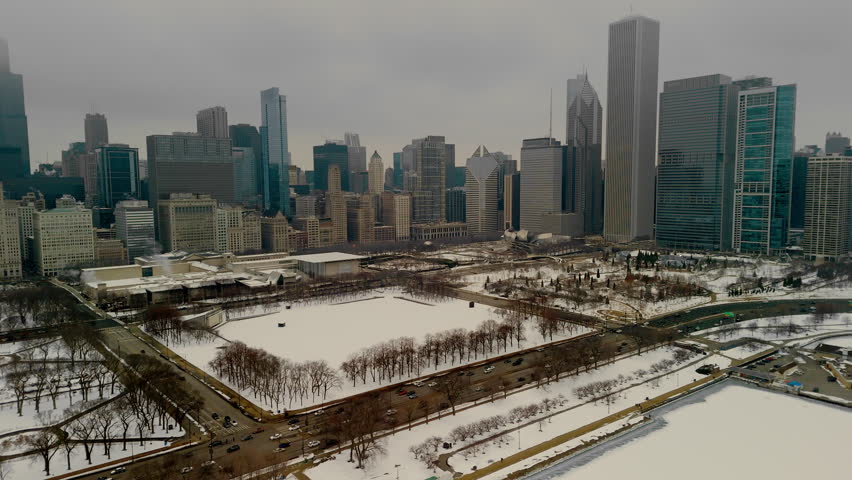 The aerial view of a snowy urban Chicago downtown. Towering buildings with Millennium concert hall, Soldier field in the background. 