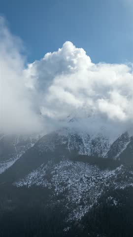 Aerial vertical hyper lapse of snowy mountains landscape with clouds motion fast
