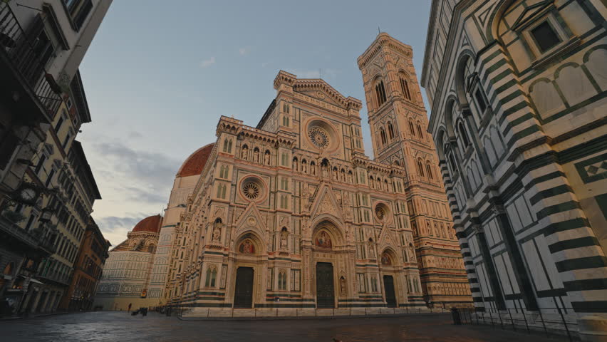 FLORENCE, ITALY - AUGUST 15 2024: Old St Mary with flower church and Giotto Bell Tower on European town square. Mosaic on facade of Santa Maria del Fiore in city district at dusk. Historic buildings