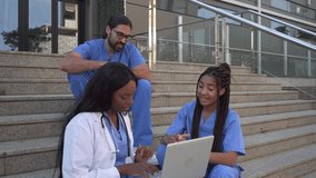 Video of Medical team discussing patient data on laptop sitting on steps outdoors - Powered by Shutterstock - Get 15% off with code: PIKWIZARD15
