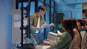 young Asian software development manager leads a late-night office discussion with his executive team, mentoring developers and analyzing source code to guide programming and project development - Powered by Shutterstock - Get 15% off with code: PIKWIZARD15