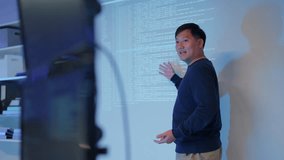 young Asian software development manager leads a late-night office discussion with his executive team, mentoring developers and analyzing source code to guide programming and project development - Powered by Shutterstock - Get 15% off with code: PIKWIZARD15