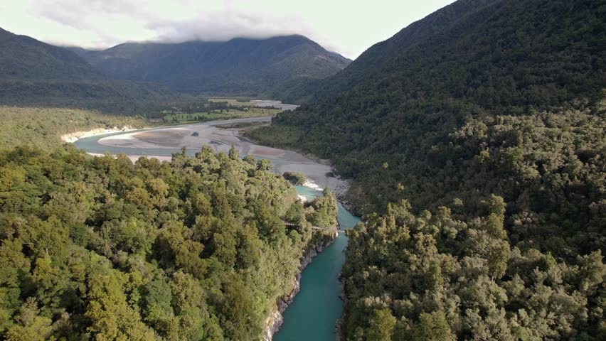 Hokitika Gorge Upper Suspension Bridge Over Hokitika River In West Coast, South Island, New Zealand. - aerial pullback shot