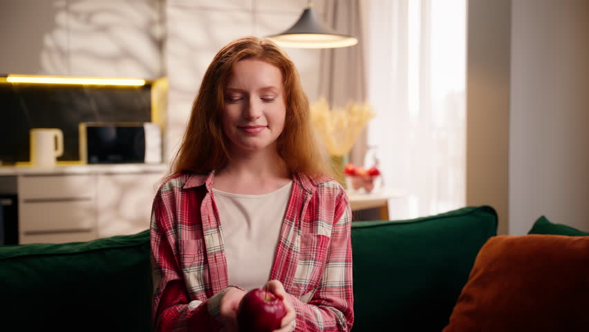 Carefree healthy Caucasian woman female teenager girl holding fruit throwing apple in air and catch smiling bite at home fit body weight control diet health nutrition eat food eco product lady eating