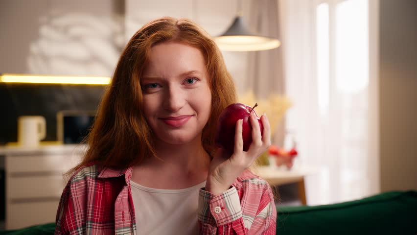 Carefree healthy Caucasian woman female teenager girl holding fruit throwing apple in air and catch smiling bite at home fit body weight control diet health nutrition eat food eco product lady eating