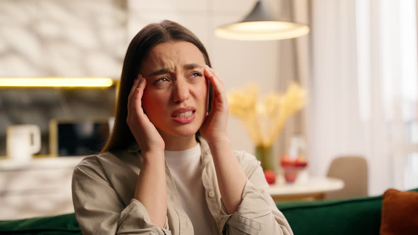 Portrait upset sad Caucasian woman girl female lady feeling headache pain ache bad symptoms head problem health medicine ill sick suffering despair at home unhappy depressed stressful in living room