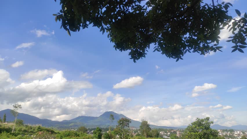 View of Mountains and Fields Under Blue Sky and White Clouds.