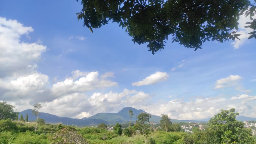 View of Mountains and Fields Under Blue Sky and White Clouds.