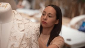 Close-up of fashion designer inspecting dress pattern on mannequin, focusing on fabric drape and precise tailoring in modern studio workspace. Seamstress examining dress on mannequin in atelier. - Powered by Shutterstock - Get 15% off with code: PIKWIZARD15