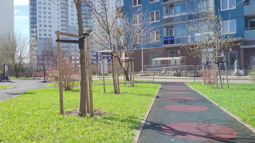 Spring path to an apartment building, a landscaped courtyard, young trees along the alley. Concept for the development of territories and adjoining space