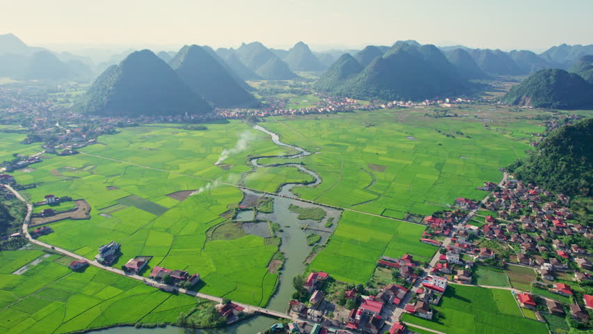 Aerial view of beautiful Bac Son Valley with lush green rice field, mountain range, winding river and suburban village in countryside at Lang Son, Vietnam