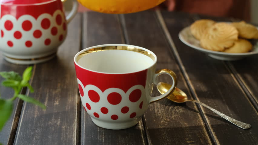 Tea party. Pouring sea buckthorn tea into mug