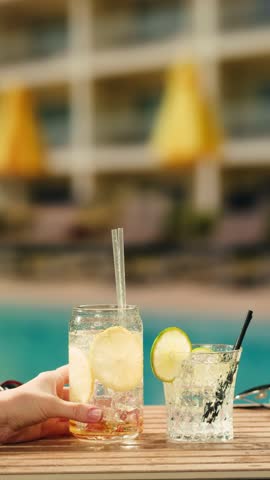 Fruit cocktail in hotel bar, Two cocktail glasses cheers in the hands on sea background. Bartenter making drink in bar, Summer vacation concept, A beautiful couple enjoy the vacation at the beach.