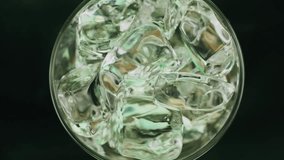 Super slow motion 1000fps top view on pouring beer on green ice cubes in rotate glass.Poured glass beer.Slow motion pouring beer on spin ice cubes in twist cup drink.Slow motion rotate turn ice cubes - Powered by Shutterstock - Get 15% off with code: PIKWIZARD15