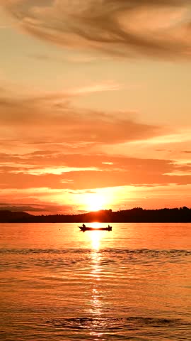 Sunset on the beach with the silhouette of mountains and fishermen with their boats at sea