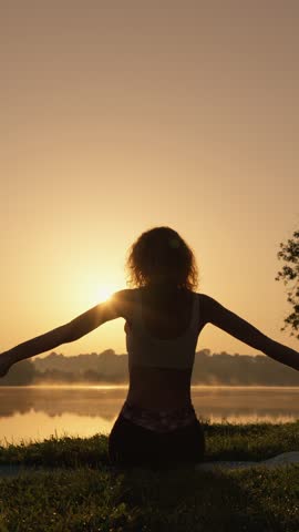 A tranquil and picturesque scene unfolds as a person peacefully meditates by the serene lakeside at sunrise, beautifully embodying calmness and a profound connection with the natural world