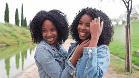 African two happy twin sisters are embracing and touching their curly afro hair, enjoying a sunny day together in a park - Powered by Shutterstock - Get 15% off with code: PIKWIZARD15