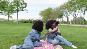 African happy twin sisters and their niece enjoying a delightful picnic in a lush green park, sharing laughter and creating joyful memories together - Powered by Shutterstock - Get 15% off with code: PIKWIZARD15