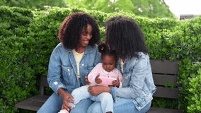 Two twin sisters enjoying time outdoors with their niece, sharing a smartphone on a park bench, creating a heartwarming family moment - Powered by Shutterstock - Get 15% off with code: PIKWIZARD15
