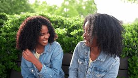Two twin sisters are sitting on a park bench, enjoying each other's company and sharing a moment of connection amidst the greenery - Powered by Shutterstock - Get 15% off with code: PIKWIZARD15