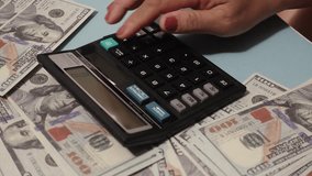 Woman hands pressing calculator buttons analyzing business income. Hand using calculator on table with spread US dollar banknotes. - Powered by Shutterstock - Get 15% off with code: PIKWIZARD15