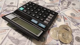 A hand operates a calculator surrounded by scattered US dollar bills and Bitcoin. Calculator and bitcoins in US dollars representing finances and cryptocurrencies - Powered by Shutterstock - Get 15% off with code: PIKWIZARD15